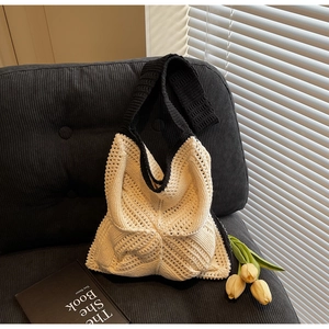 Detail of hollow crochet tote bag in black and white knit texture on a cozy sofa
