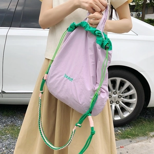 Detail of lavender nylon bag with green drawstring and embroidered beaut logo