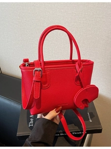 Chic red lychee pattern handbag with cute elephant charm and adjustable strap