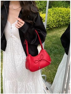 Detail of red pebbled leather underarm bag with decorative bow and silver hardware