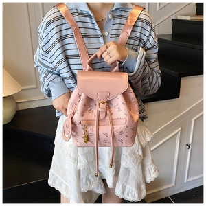 Pink backpack detail showing cartoon bear patterns, heart metal lock, and smiley pendant