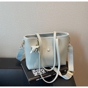Detail of mint green lychee grain leather tote with elephant charm and woven strap