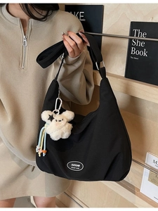 Black canvas crescent hobo bag with adjustable strap and plush bunny charm detail