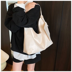 Detailed view of beige faux leather tote bag with unique knotted strap and spacious design