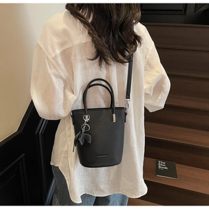 Detail showing the textured black leather bucket bag with cute elephant charm and strap