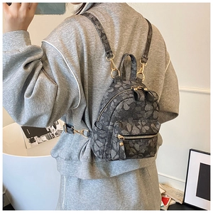 Detail of a mini floral jacquard backpack worn as a versatile crossbody and shoulder bag