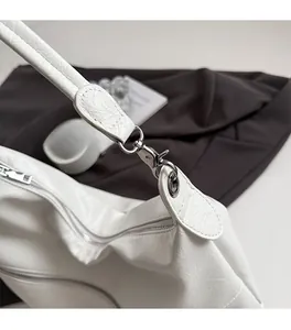 Detail view of the white tote bag showing silver metal hooks and zipper closure texture