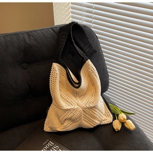 Close-up of handmade crochet tote bag with cream openwork pattern and black knit borders