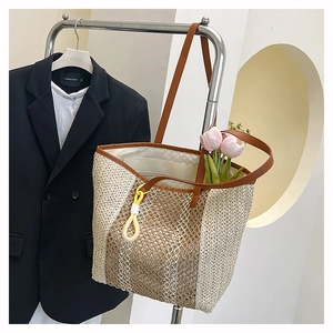 Detailed texture of woven straw beach tote bag with brown straps and vertical stripes