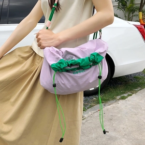 Detail of nylon drawstring crossbody bag with green embroidery and purple fabric texture