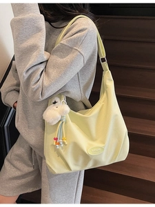 Chic canvas hobo bag with grid texture and plush dog pendant on a wooden staircase