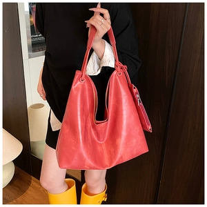 Detail of red faux leather tote bag with wide strap and matching zipper pouch charm