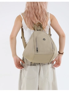 Rear view of a light beige nylon backpack showing adjustable straps and its sleek profile