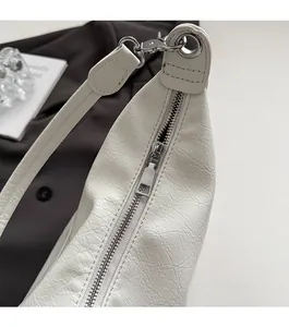 Detailed close-up of smooth silver zipper and lychee leather texture on a white bag