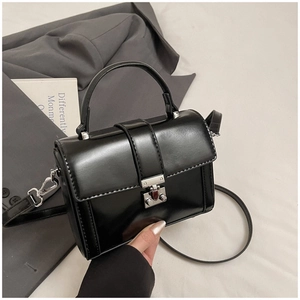 Detailed close-up of a black leather crossbody bag with a silver twist-lock and handle