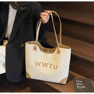 Detail of a large white and brown tote bag with WWTU lettering in a street style setting
