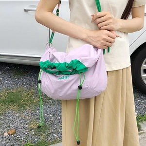 Detail of lavender nylon drawstring crossbody bag with green contrast cord and embroidery