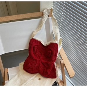 Detailed close-up of handmade red floral crochet bag with tassel and cream shoulder strap