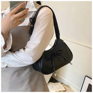 Detail of black pebbled leather dumpling bag featuring bow knot accents and metallic zipper