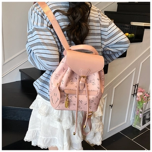 Detail of pink bear print backpack with pebble texture worn by model on stairs