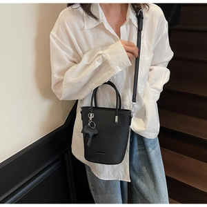 Close-up of black lychee grain leather bucket bag featuring a cute puppy charm detail