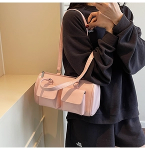 Detail of a pink glossy bowling bag with double front pockets on a female model