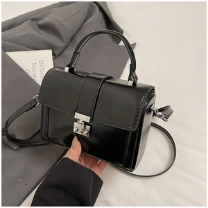 Detail of black glossy leather handbag featuring silver metal clasp and fine stitching