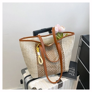 Close-up of woven straw beach tote bag featuring brown leather trim and tassel detail