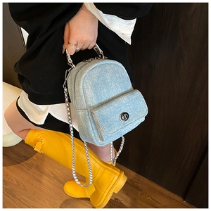 Detailed close-up of mini denim backpack featuring silver chain and metal turn-lock