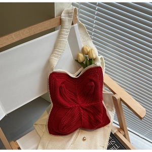 Close-up of red and white crochet shoulder bag with hand-woven floral patterns and strap