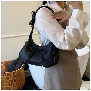 Detail of black bow shoulder bag featuring lychee grain leather and elegant bow tie details