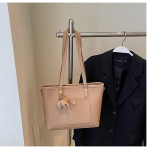 Detail view of khaki lychee grain tote bag with decorative elephant charm and long handles