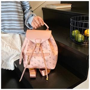 Detailed view of pink faux leather backpack with cartoon bear pattern and flap buckle closure
