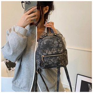 Detail of floral mini backpack showing the jacquard fabric texture and golden metal hardware