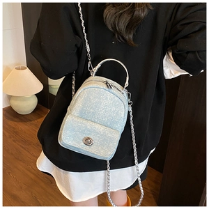 Detail of light blue tweed texture backpack with silver chain strap and metal lock