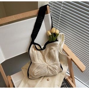 Detail of star-shaped crochet tote bag with black trim on white chair with tulip