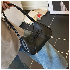 Detailed macro view of black lychee grain leather handbag with stylish bow knot decor