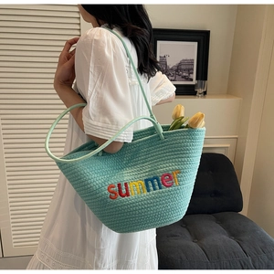 Detail of mint green woven tote with colorful summer embroidery on a stylish strap