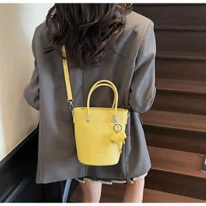 Macro detail of yellow bucket bag with lychee grain texture and elephant charm accessory
