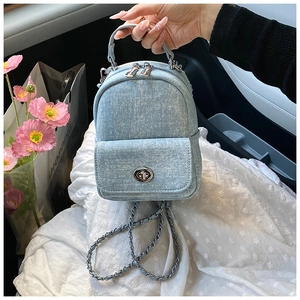 Detail of light blue denim mini backpack featuring metal twist-lock and chain strap