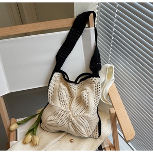 Detail of crochet tote bag with black and white star pattern on a wooden chair