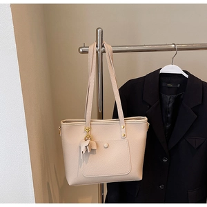 Detail of beige lychee pattern tote bag with elephant charm on metal hanger