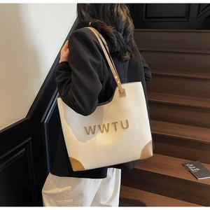 Rear view of a model wearing a cream and brown large tote bag on stairs