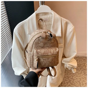 Detail of mini beige backpack showing embossed texture and dual zipper compartments