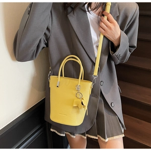 Detailed macro view of yellow pebbled leather bucket bag with top handle and leaf charm