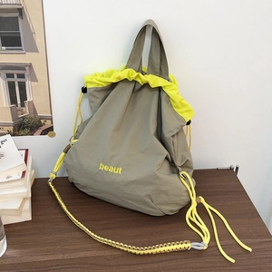 Detail of olive nylon crossbody bag with yellow drawstring and beaut embroidery