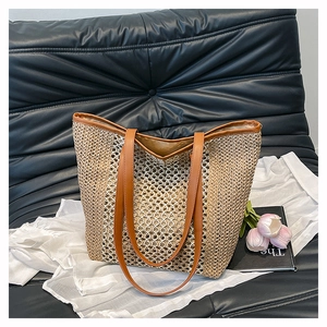 Close-up of a woven straw beach bag featuring brown leather handles and mesh texture