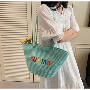 Detail of light green woven tote bag with colorful summer embroidery and rope handle
