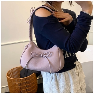 Close-up of light purple textured hobo bag with elegant bow details on model shoulder