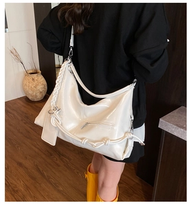 Detail view of a white glossy hobo bag featuring woven straps and polished texture